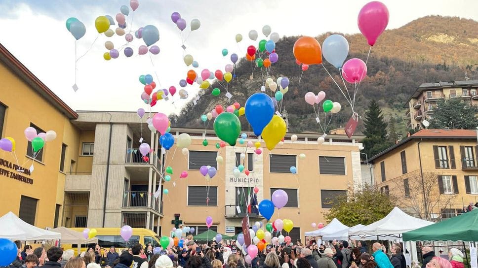 Il momento del lancio dei palloncini a Caslino d’Erba con tantissimi bambini in piazza. In alto l’appello degli ambientalisti  (Bartesaghi)