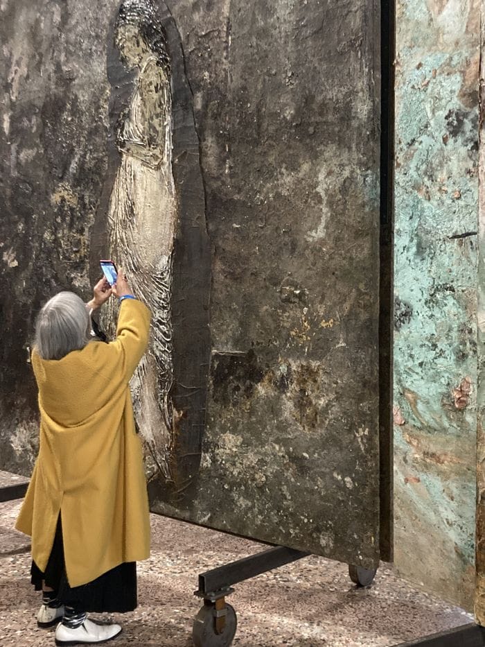 Una delle Alchimiste rappresentate da Kiefer fotografata da una visitatrice: i grandi teleri (maxi paraventi) sovrastano chi li ammira