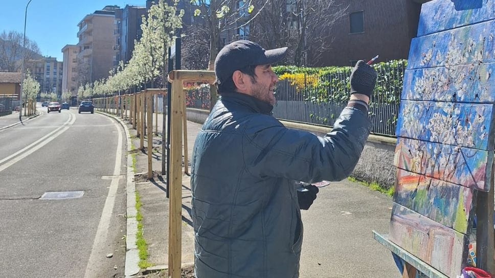 Il pittore Camolgion Babaev mentre immortala i peri in fiore piantati in via Aldo Moro