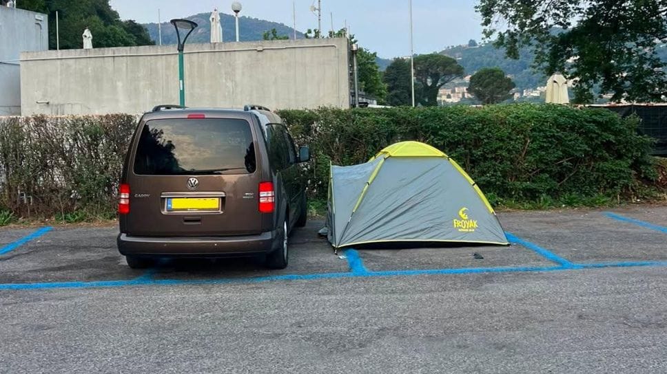 Campeggio improvvisato in viale Geno: tenda piazzata negli stalli blu